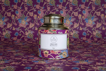 Decorative tea canister with colorful label on a wooden surface
