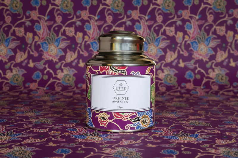 Decorative tea canister with colorful label on a wooden surface