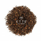 Dry black tea leaves with 'ETTE Tea Company' logo on a white background